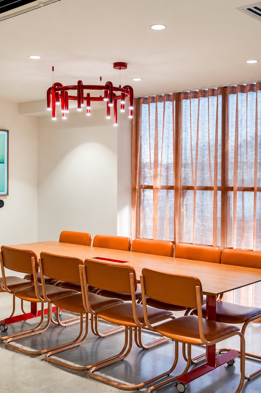 Boardroom table with orange leather chairs and red pendant light